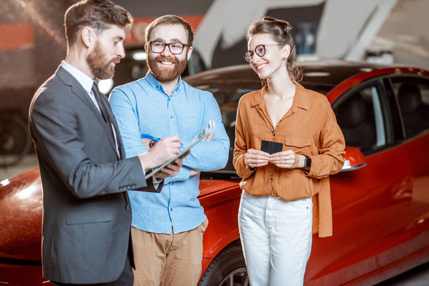 Couple with sales manager in the car dealership - 写真・画像