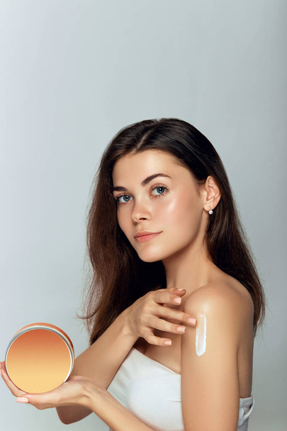 Beauty face model. Beautiful Woman with healthy  facial clean skin holding bottle cosmetic cream. Face Skin care Moisturizer Facial treatment. Cosmetology. Spa. - Fotografie, Obrázek