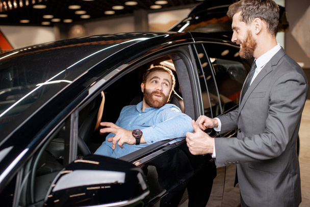 Kierownik sprzedaży z klientem patrzącym na wnętrze pojazdu - Zdjęcie, obraz