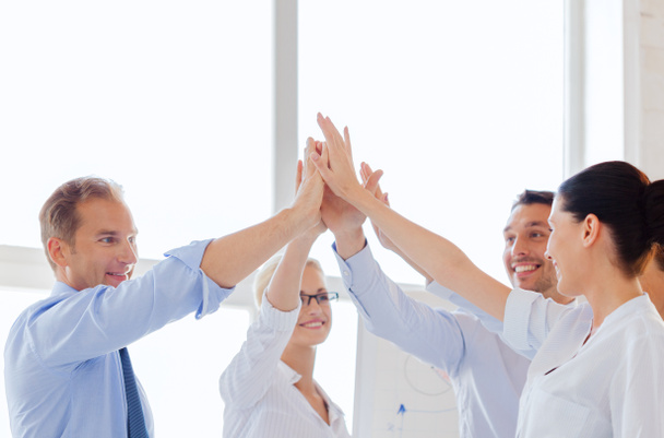 Happy business team giving high five in office - Photo, Image