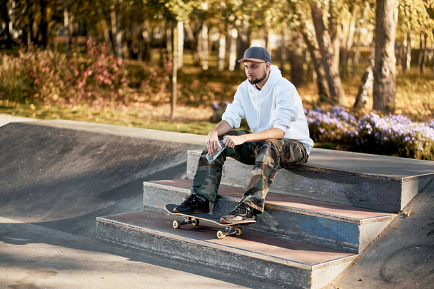 Man in skatepark with skateboard on warm autumn day - Zdjęcie, obraz