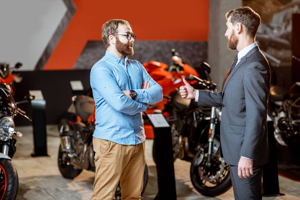 Consultor de ventas con un cliente en el showroom con motocicletas
 - Foto, imagen