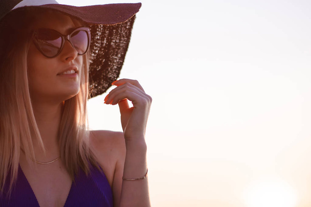 retrato de una joven con sombrero y gafas de sol en la playa al amanecer
 - Foto, Imagen