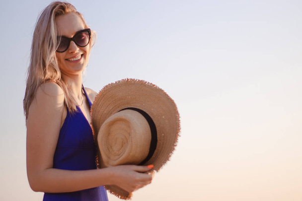 портрет молодой женщины в шляпе и солнцезащитных очках на пляже на рассвете
 - Фото, изображение