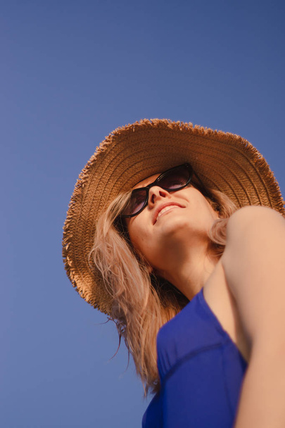 portrait of a young woman in a hat and sunglasses on the beach at sunrise - Фото, изображение