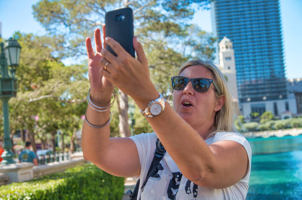 Boldog nő napszemüveggel látogat el a nagyvárosba nyáron, hogy szelfiket csináljon okostelefonnal. Utazási, üdülési és nyaralási koncepció - Fotó, kép