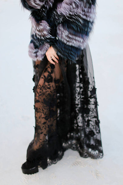 雪の上に黒い透明なドレスを着た女性. - 写真・画像