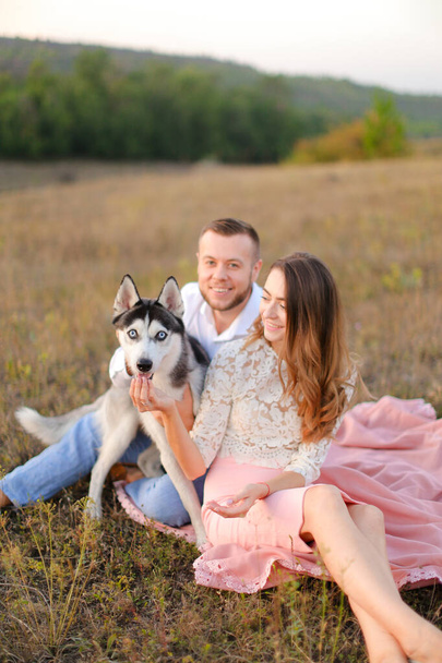 Young girl and man sitting on gras with husky. - 写真・画像