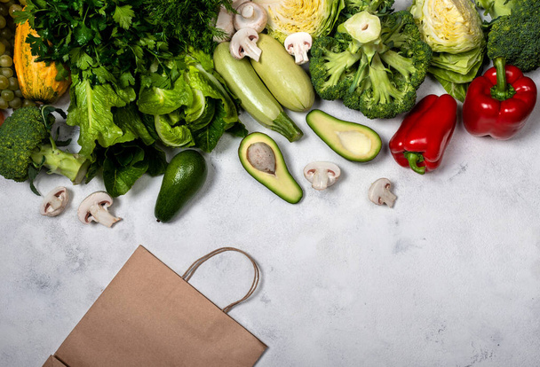 Compra comida vegetariana saludable. Diferentes verduras frescas y bolsa de papel sobre un fondo claro. Vista superior con lugar para texto
. - Foto, imagen