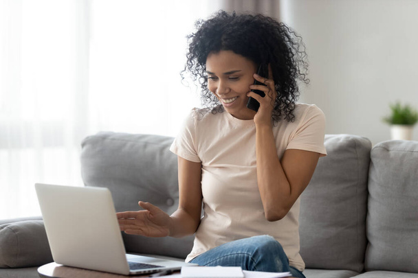 Smiling black woman multitask at home using gadgets - Zdjęcie, obraz