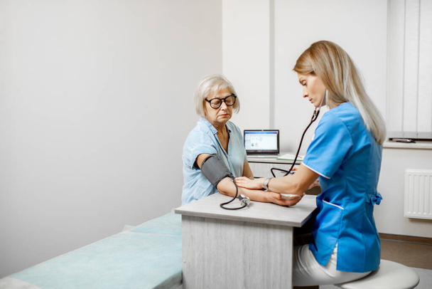 Enfermera midiendo la presión arterial de un paciente mayor
 - Foto, imagen