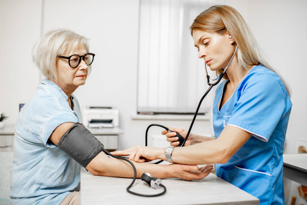 Nurse measuring blood pressure of a senior patient - 写真・画像