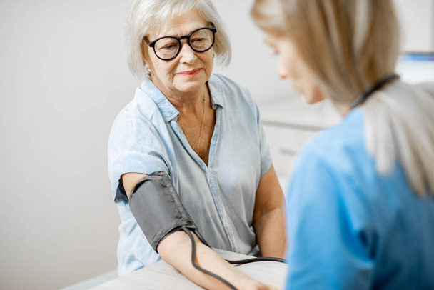 Nurse measuring blood pressure of a senior patient - Foto, imagen