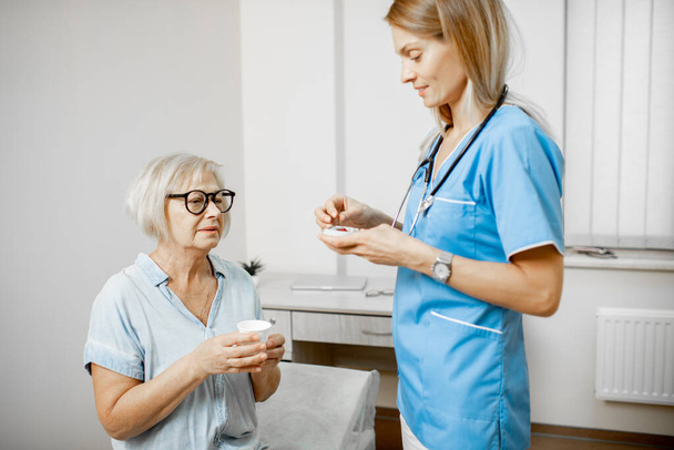 Νοσοκόμα που δίνει κάποιο φάρμακο για έναν ηλικιωμένο ασθενή - Φωτογραφία, εικόνα