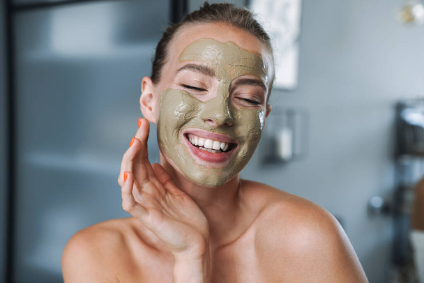 Young woman at home after spa taking care of her skin with face mask. - Foto, immagini