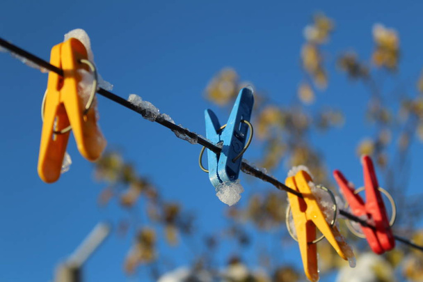 Прищепки для сушки одежды на веревке в холодную осень / цветные фото clothespins.they прикреплены к clothesline.rope на улице во дворе.
. - Фото, изображение