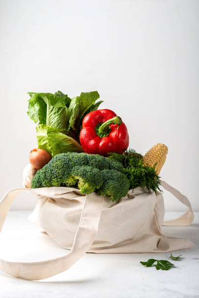 Grocery eco bag with different fresh vegetables on a light background. Zero waste purchases concept. - 写真・画像