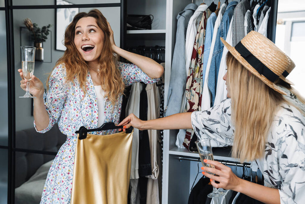 Women at home choosing clothes from closet in bedroom. - 写真・画像