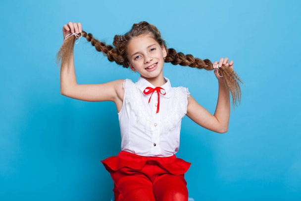 portrait of a beautiful schoolgirl with pigtails on blue background - Фото, изображение