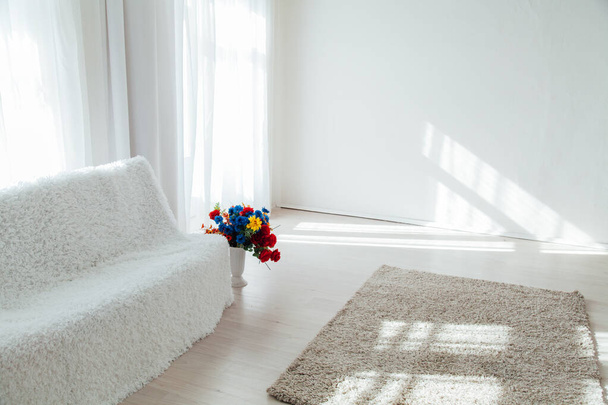 λευκός καναπές με λουλούδια στέκεται μόνος στο λευκό δωμάτιο - Φωτογραφία, εικόνα