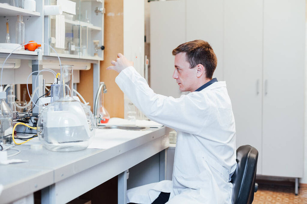 maschio giovane scienziato conduce esperimenti chimici con liquidi in laboratorio
 - Foto, immagini