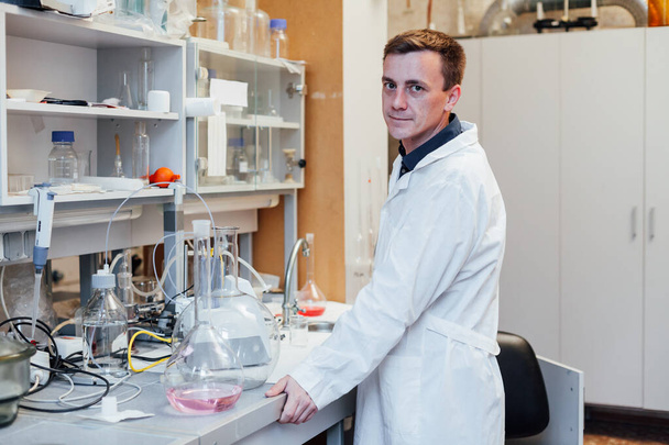 αρσενικός χημικός διεξάγει πειράματα με υγρά σε χημικό εργαστήριο - Φωτογραφία, εικόνα
