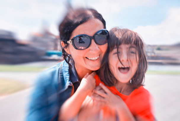 Lachende gezichten van het meisje en haar moeder tijdens een bezoek aan de stad. H - Foto, afbeelding