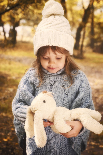 a little girl with a toy rabbit in autumn park - 写真・画像