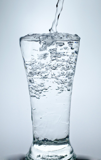 Наполнение стакана водой, показывающей концепцию напитка
 - Фото, изображение