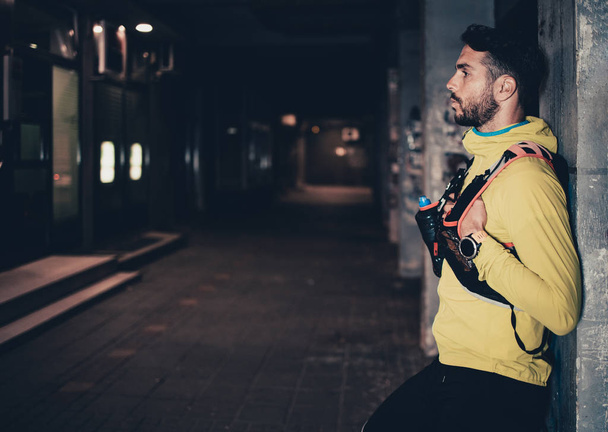 Night city fitness. Good looking man jogging on street. - Foto, Imagen