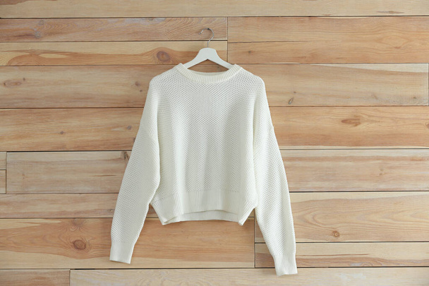 Hanger with stylish sweater on wooden wall - Fotó, kép