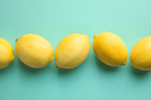 Fresh lemons on turquoise background, flat lay - Фото, изображение