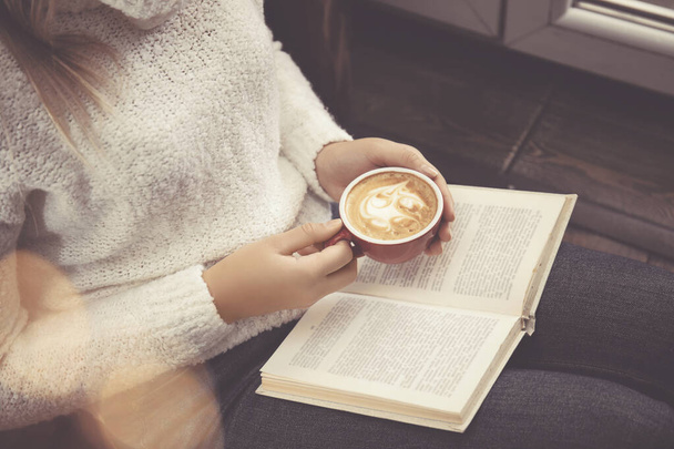 Woman with cup of coffee reading book at home, closeup - Foto, Bild