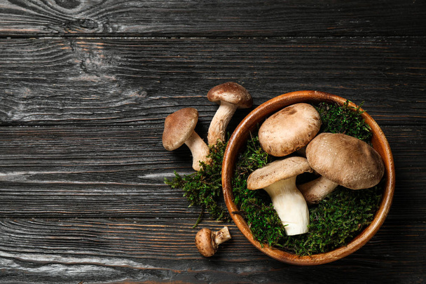 Flat lay composition with fresh wild mushrooms on black wooden table, space for text - Fotografie, Obrázek