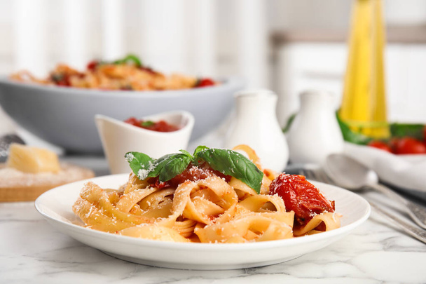 Tasty pasta with cheese, tomato sauce and basil on white marble table - Foto, Imagem