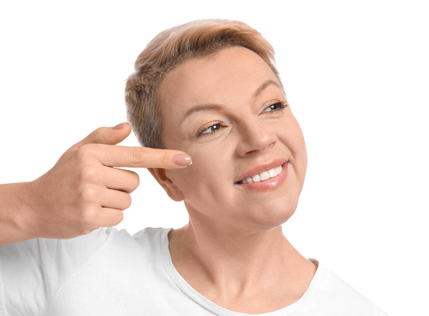 Mature woman applying face cream on white background - Foto, afbeelding