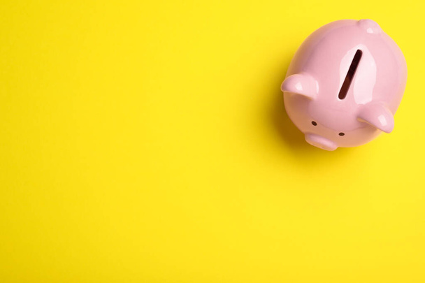 Top view of piggy bank on yellow background, space for text. Money savings - Foto, immagini