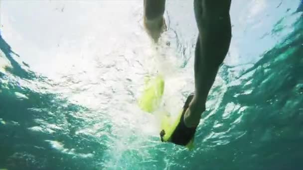 Blick in Zeitlupe von unten auf Füße in Schwimmflossen, die im transparenten Meerwasser schwimmen. Bali, Indonesien - Filmmaterial, Video