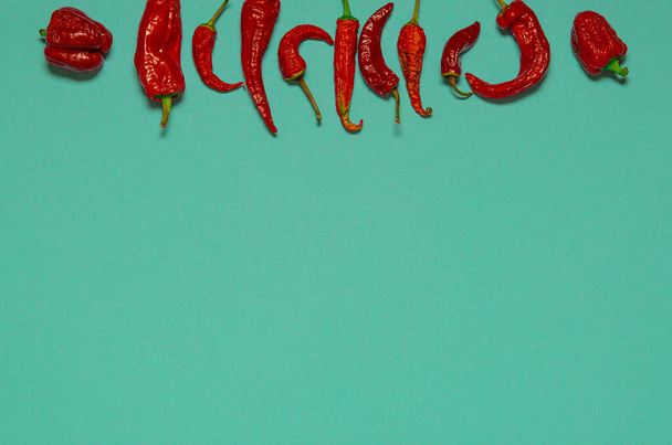 Ξηρές κόκκινες πιπεριές τσίλι βρίσκονται σε πολύχρωμο φόντο - Φωτογραφία, εικόνα