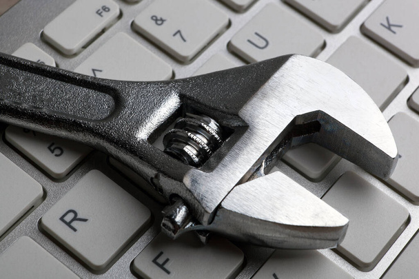 adjustable wrench and a computer keyboard close up - Fotografie, Obrázek