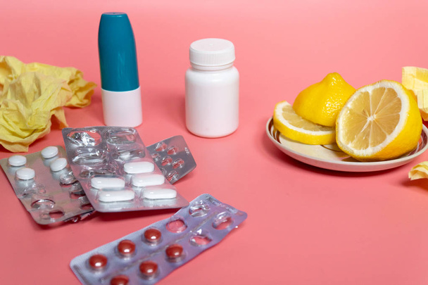 koncepcja zimna: plasterki cytryny z tabletkami na przeziębienie i aerozol do nosa na różowym tle - Zdjęcie, obraz