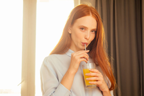 beautuful redhaired ginger woman useing eco tubes for drink smoothie at home,sunset sun light background - Photo, image