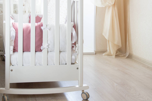 Lit bébé berceau avec oreillers de couleur blanc et bourgogne avec lacets
 - Photo, image