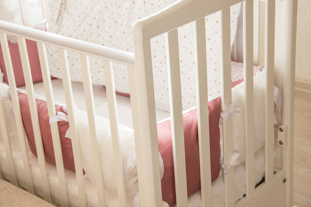 Детская кроватка с белыми и бургундскими подушками со шнурками
 - Фото, изображение