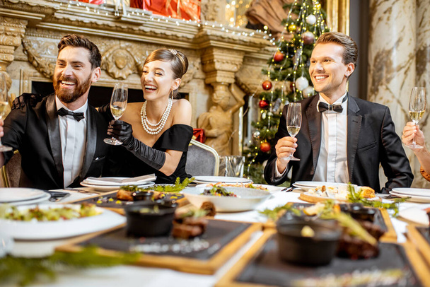 Κομψά ντυμένοι άνθρωποι που έχουν ένα εορταστικό δείπνο σε εσωτερικούς χώρους - Φωτογραφία, εικόνα