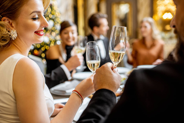 Элегантно одетые люди устраивают праздничный ужин в помещении
 - Фото, изображение