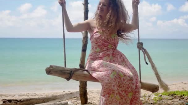 fröhliche Frau reitet selbstgebastelte Schaukel am Strand - Filmmaterial, Video