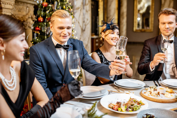 Elegantly dressed people having a festive dinner indoors - Photo, Image