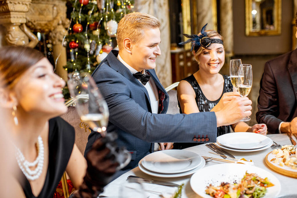 Elegantemente vestidos personas teniendo una cena festiva en el interior
 - Foto, imagen