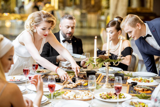 Elegantly dressed people having a festive dinner indoors - 写真・画像